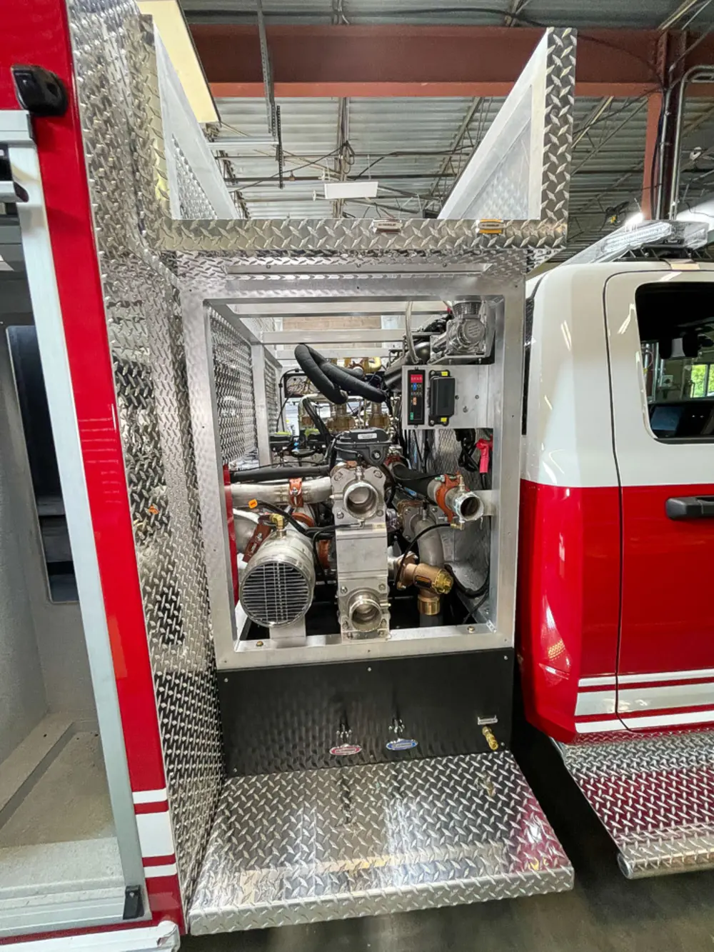 Exterior view of small fire truck showing cab, body compartments, and wheel/tire area.